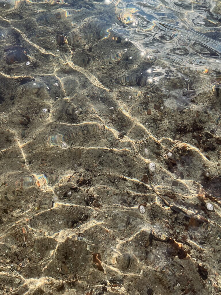Photograph of a lake water where sun and waves make figures